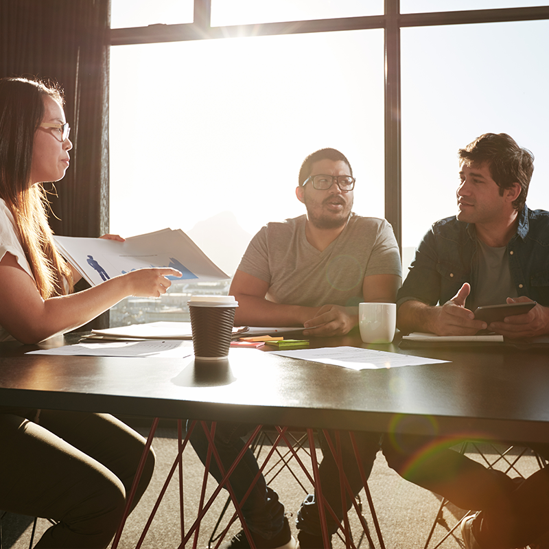 Three individuals engaged in a discussion around a table